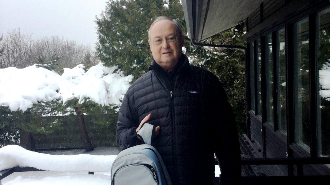 Mann in Winterkleidung steht im verschneiten Außenbereich und hält eine COOL*SAFE Medikamentenkühltasche in Rucksackform in der Hand.