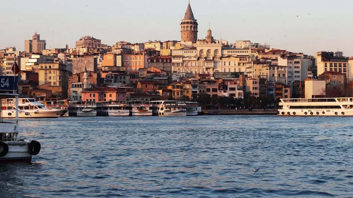 Blick über das Wasser auf die Altstadt von Istanbul mit dem markanten Galataturm im Hintergrund und mehreren Fähren im Vordergrund.