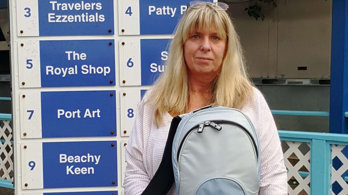 Frau mit COOL*SAFE Medikamentenkühltasche steht vor einem Wegweiser am Kreuzfahrtterminal Montego Bay auf Jamaika.